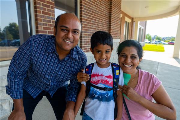 mom, dad and boy student holding hands